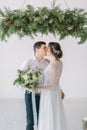 Close up of a nice young wedding couple. Wedding ceremony in light white room decorated with pine, flowers and candles.