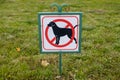 Close-up of no dog sign. Street pointer on a background of green grass. Ban on defecation and running of pets on park lawns and