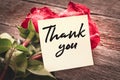 Close-up note with the words Thank you on a bouquet of red roses on a wooden background: the concept of gratitude and appreciation Royalty Free Stock Photo