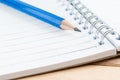 Close-up notebook and blue pencil on wood table Royalty Free Stock Photo