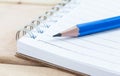 Close-up notebook and blue pencil on wood table Royalty Free Stock Photo