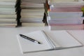 Close up of notebook with ink-pen and eyeglasses put on white table with blur focus of books as a background. Royalty Free Stock Photo