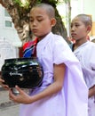 Close up of Novice nun with black alms bowl looking serious, Myanmar