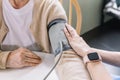 Close up nurse hand measuring blood pressure of senior woman with care. Caregiver visit at home. Home health care and nursing home Royalty Free Stock Photo