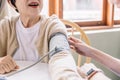 Close up nurse hand measuring blood pressure of senior woman with care. Caregiver visit at home. Home health care and nursing home Royalty Free Stock Photo