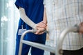 Close up of nurse help disable man walk with walker at nursing home. Caregiver therapist doctor support senior older handicapped Royalty Free Stock Photo