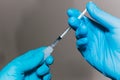 Close-up of a nurse`s gloved hands inserting a vaccine into a syringe