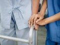 Close-up of nurse`s hands, assistant in blue suit holding elderly or older woman`s hands for support.