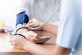 Close-up of nurse with stethoscope checking blood pressure of se