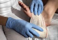Close-up Of A Nurse Tying Bandage On Patient`s Foot
