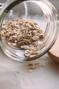 Close up of oat flakes dropped from glass jar on table. Healthy breakfast food. Vertical