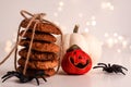 Close up of oatmeal cookies in a stack tied with brown thread and halloween black spiders white and orange small pumpkin on bright