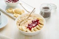 Close up of oatmeal porridge, healthy vegan diet breakfast with strawberry jam, peanut butter, banana, chia on white wooden light Royalty Free Stock Photo