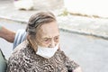 close-up of an octogenarian woman walking down the street in a wheelchair