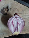 Close up off a splitted purple onion on an olive wood chopping board featuring a sharp Japanese blade in the background