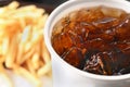 Close-up of oily French fries and soft drink