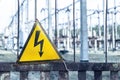 Close-up old aged rusty triangle metal plate with High voltage warning sign. Power station with transformers and Royalty Free Stock Photo