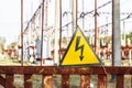 Close-up old aged rusty triangle metal plate with High voltage warning sign. Power station with transformers and electricity Royalty Free Stock Photo