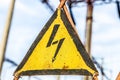 Close-up old aged rusty triangle metal plate with High voltage warning sign. Power station with transformers and electricity distr Royalty Free Stock Photo