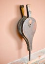 close up of an old bellows made in leather and wood. The bellows in vertical position is rested on a wall of bricks and an a brown