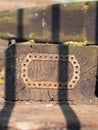Close-up of an old block of wood with a piece of iron with holes attached on the surface.