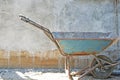 Old blue wheelbarrow on concrete blocks wall background Royalty Free Stock Photo