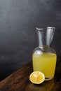 Close-up of old bottle with lemonade and half lemon on wooden table and gray background in vertical Royalty Free Stock Photo