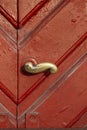 Close up of old brass door handle on a weathered red wooden door Royalty Free Stock Photo