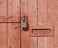 Close up of an old brown wooden door with faded paint and a rusty closed padlock and old metal letterbox Royalty Free Stock Photo