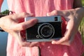 Close-up of old camera in hands. Young woman in pink t-shirt holding vintage film camera. Royalty Free Stock Photo