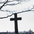 Close-up old christian cross in a cemetery on a background of trees branches and light sky. Cemetery concept Royalty Free Stock Photo