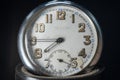 Close up of an An old clock face with numbers. Scratches on the glass. Silver chrome metal. Black background
