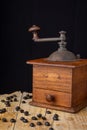 Close-up of old coffee grinder with coffee beans on wooden table and black background Royalty Free Stock Photo