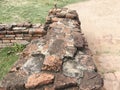 Old crumbling overgrown brick wall in front of stupa at historic park thailand Royalty Free Stock Photo