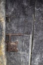 Close up of an old and deteriorated wooden door with a rusty metal latch and a padlock, rural texture Royalty Free Stock Photo