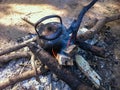Close up of old, dirty teapot with water warming on the fire in touristic camp.