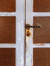 Close up of old door with rusty latch and lock. Rust on metal lock and rotten wooden door. Architecture and construction details Royalty Free Stock Photo