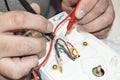 Close-up of the old electrician`s hand, the use of digital voltmeter for voltage to repair the electric iron, selective Royalty Free Stock Photo