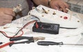 Close-up of the old electrician`s hand, the use of digital voltmeter for voltage to repair the electric iron, selective Royalty Free Stock Photo