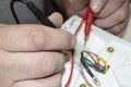 Close-up of the old electrician`s hand, the use of digital voltmeter for voltage to repair the electric iron, selective Royalty Free Stock Photo