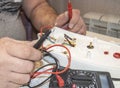 Close-up of the old electrician`s hand, the use of digital voltmeter for voltage to repair the electric iron, selective Royalty Free Stock Photo