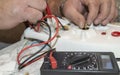 Close-up of the old electrician`s hand, the use of digital voltmeter for voltage to repair the electric iron, selective Royalty Free Stock Photo