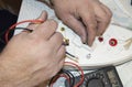 Close-up of the old electrician`s hand, the use of digital voltmeter for voltage to repair the electric iron, selective Royalty Free Stock Photo