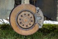 Close-up of old forsaken abandoned rusty broken trash car brake disc detail without rubber tire outdoors in field