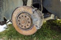 Close-up of old forsaken abandoned rusty broken trash car brake disc detail without rubber tire outdoors in field