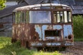 Close-up of old forsaken passenger bus with broken windows rusting in high green weedy grass on edge of plowed brown field on Royalty Free Stock Photo