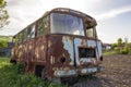 Close-up of old forsaken passenger bus with broken windows rusting in high green weedy grass on edge of plowed brown field on brig Royalty Free Stock Photo