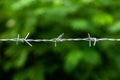 Close-up of an old iron barbed fence and a soft focus green bokeh background Royalty Free Stock Photo