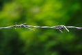 Close-up of an old iron barbed fence and a soft focus green bokeh background Royalty Free Stock Photo