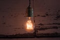 Close-up of old lit bulb, worn wooden background